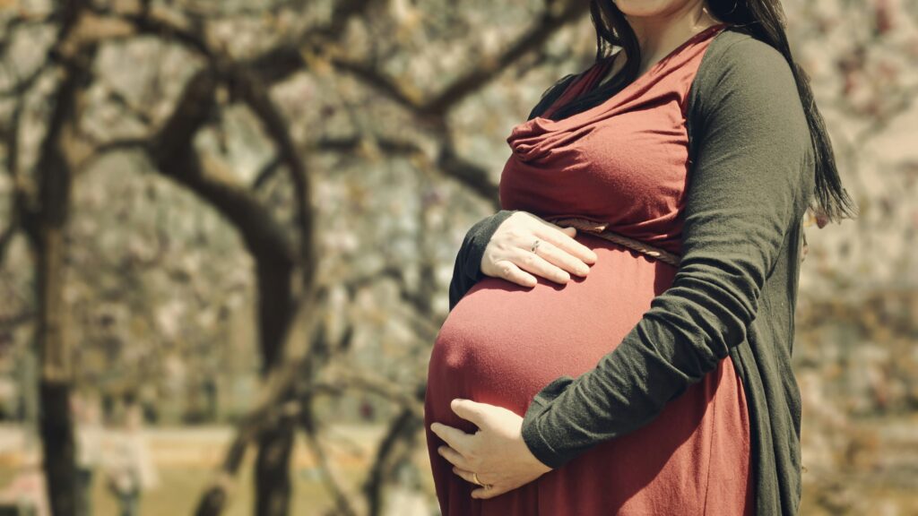 Mulher grávida segurando a barriga, representando a relação entre o consumo de cafeína na gravidez e o desenvolvimento infantil.