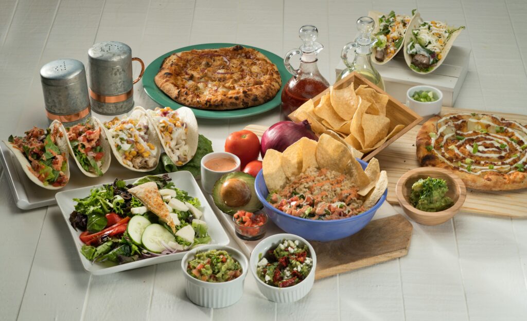 Mesa com vários alimentos dispostos representando alguns motivos de uma pessoa não conseguir baixar o colesterol.