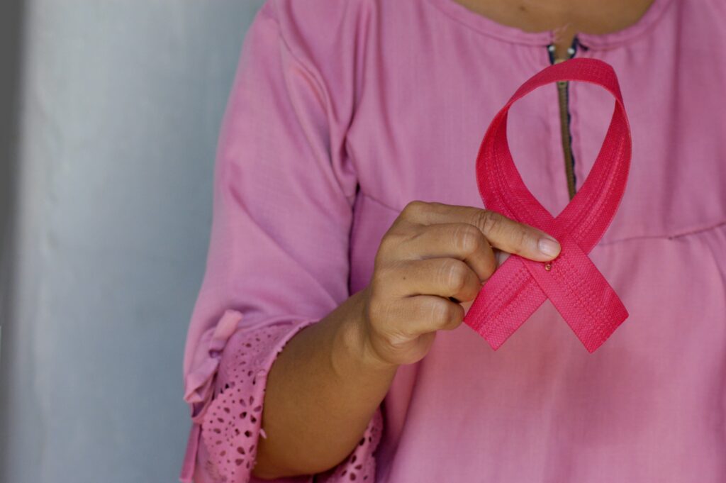 Imagem de uma mulher segurando uma fita rosa simbolizando o combate ao câncer de mama. Foto de Angiola Harry na Unsplash